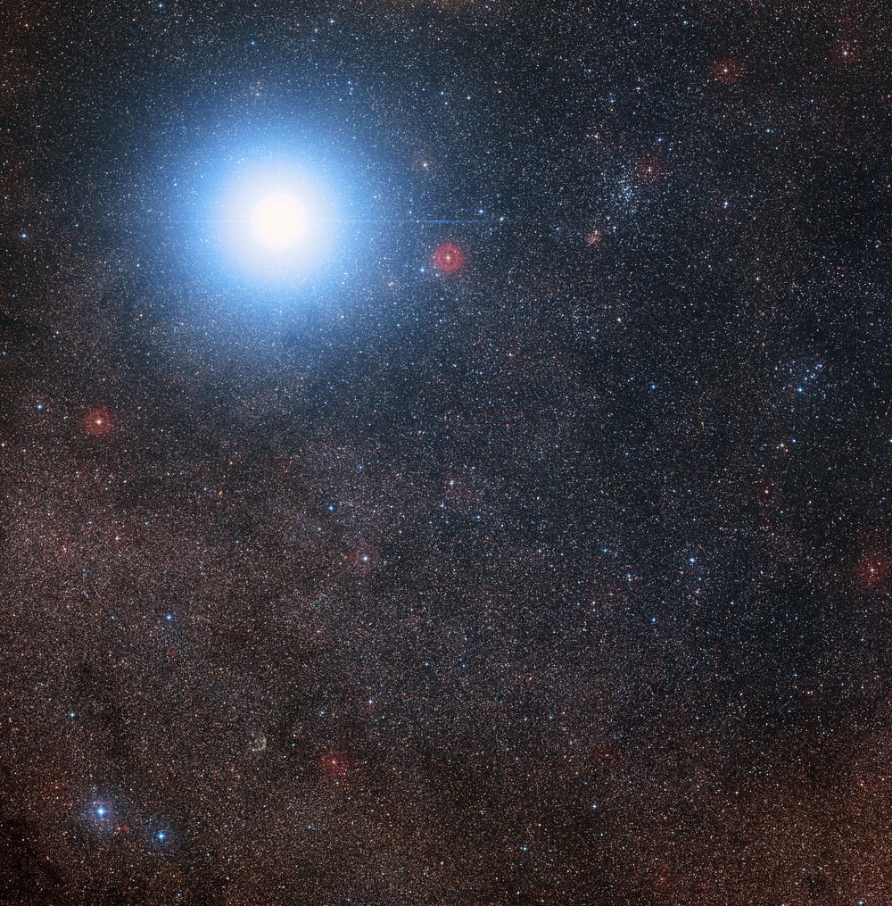 Üst kısma yakın mavi büyük yıldız aslında Alfa Centauri AB adındaki iki yıldız sistemi. Yakındaki kızıl cüce ise Proxima Centauri. 