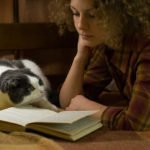 Girl and a cat reading an open book